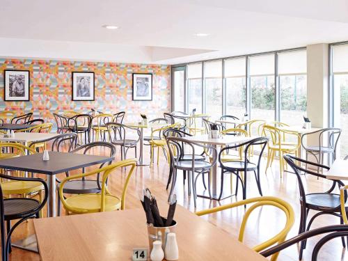a dining room with tables and chairs and windows at ibis Styles Barnsley in Barnsley
