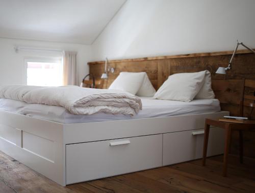 a large white bed with white sheets and pillows at Chalet Swiss Andermatt in Andermatt
