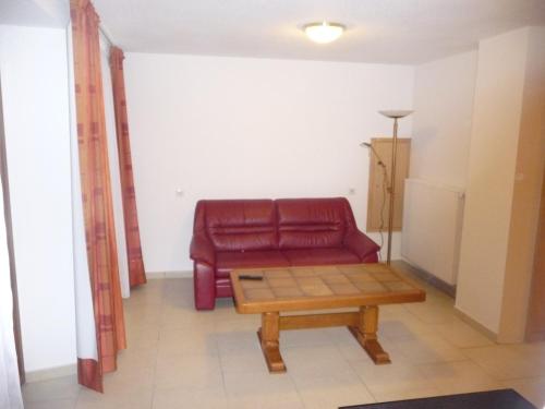 a living room with a red couch and a coffee table at Relais du Klevener in Heiligenstein