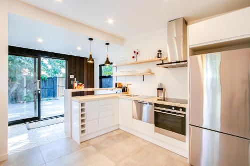 a kitchen with white cabinets and a large window at Beach and Vineyard Escape - Haumoana Beach Home in Haumoana