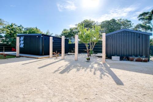 two blue shipping containers with a tree in the sand at Beach and Vineyard Escape - Haumoana Beach Home in Haumoana