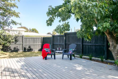 two chairs and a table with a red blanket on a patio at Beach and Vineyard Escape - Haumoana Beach Home in Haumoana