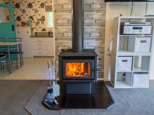 a stove in a living room with a kitchen at Vista Lagoon - Kaiteriteri Holiday Unit in Kaiteriteri