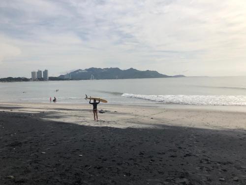 a person walking on the beach with a surfboard at Casa Swell Coronado A unique blend of luxury and nature in the hearth of Coronado in Playa Coronado