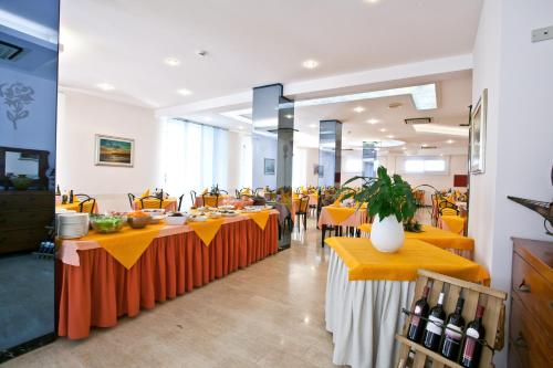 ベッラーリア・イジェア・マリーナにあるHotel Theaの長テーブル(オレンジのテーブルクロス付)のあるレストラン