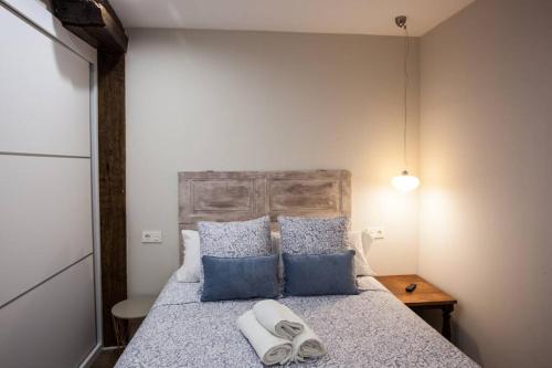 a bedroom with a bed with blue and white pillows at BONITO APARTAMENTO, NUEVO Y EN EL CASCO VIEJO!!! in Bilbao
