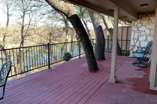 a porch with two trees and benches on a balcony at Home On the Green in Salado