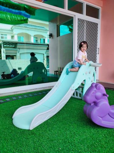 a little girl is sitting on a slide at 歐拉民宿 l 大空間包棟 l 親子溜滑梯 l 專業音響 in Taitung City
