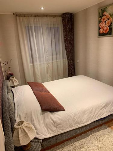 Schlafzimmer mit einem Bett mit weißer Bettwäsche und einem Fenster in der Unterkunft Apartment in Daugavpils Centre in Daugavpils