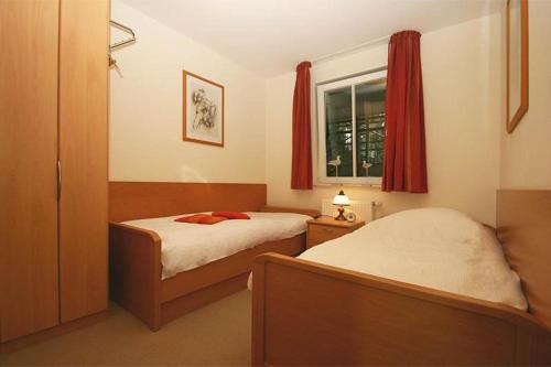 キュールングスボルンにあるHaus-Meeresblick-Wohnung-2-11-322のベッドルーム1室(ベッド2台付)、赤いカーテン付きの窓が備わります。