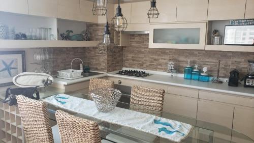 a kitchen with a table and some chairs and a sink at Departamento Laguna Bahia, Algarrobo in Algarrobo
