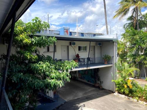 a white house with a balcony and trees at Cairns City Motel in Cairns