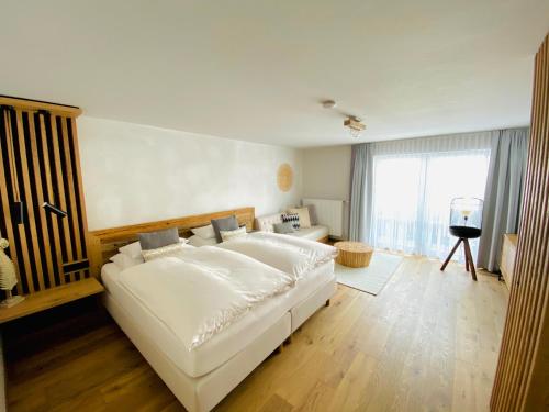 a bedroom with a large white bed and a large window at Verweilzeit Appartementhaus in Ramsau am Dachstein