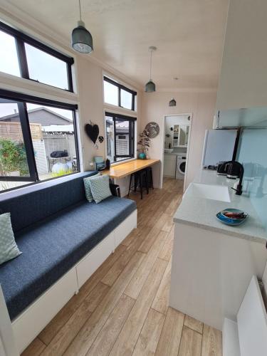 a living room with a blue couch and a kitchen at Aroha Tiny House Peka Peka in Waikanae