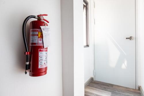 a fire extinguisher hanging on a wall next to a door at Baan Kun Mhor Hostel บ้านคุณหมอโฮสเทล in Bangkok