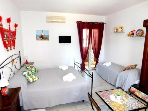 2 łóżka w pokoju z czerwonymi zasłonami w obiekcie Sicilia Room w mieście Carrozziere