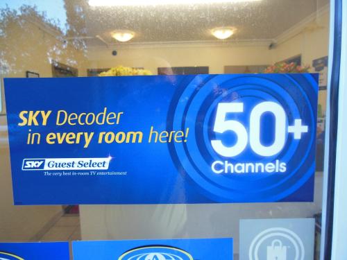 a sign on the window of a store with a sky detector in every room at ASURE Camelot Arms Motor Lodge in Auckland