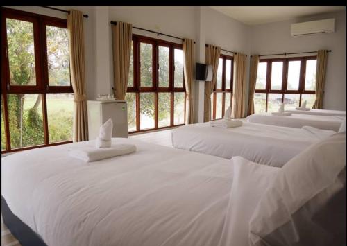 two white beds in a room with windows at Oon Valley Farm Stay in Ban Mae Pha Haen