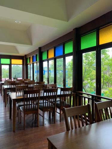 a restaurant with tables and chairs and colorful windows at Oon Valley Farm Stay in Ban Mae Pha Haen