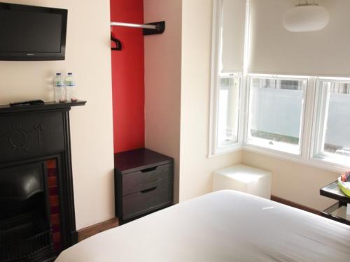 a bedroom with a bed and a tv and a window at Guest And The City in Brighton & Hove