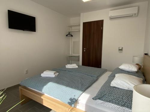 two beds in a room with a tv on the wall at Sulyom Panzió in Tiszafüred