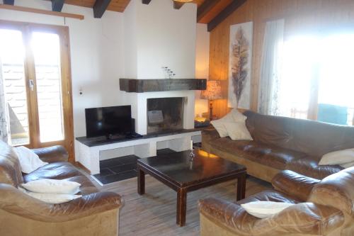 ein Wohnzimmer mit Ledersofas und einem Kamin in der Unterkunft Melezes K SKI LIFT & NATURE apartments by Alpvision Résidences in Veysonnaz