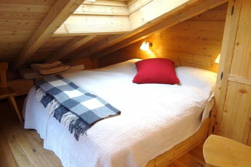 uma cama num chalé de madeira com uma almofada vermelha em Diableret 051 SUBLIME & MOUNTAIN apartment 6 pers by Alpvision Résidences em Veysonnaz
