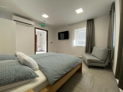 ein Schlafzimmer mit einem Bett, einem Stuhl und einem Fenster in der Unterkunft Sulyom Panzió in Tiszafüred
