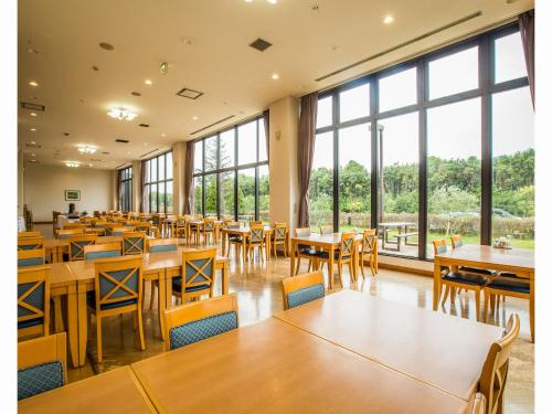 uma sala de jantar com mesas e cadeiras e janelas grandes em Blue Port Hotel Kitakyushu Airport em Kanda