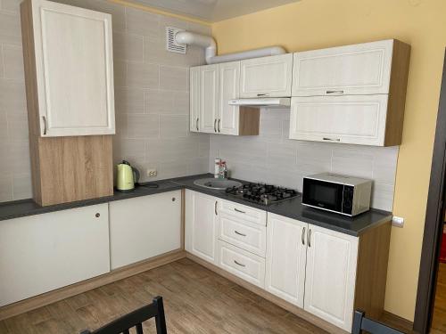 Apartments at Okruzhnaya 3 في زيلينوغرادسك: مطبخ مع دواليب بيضاء وميكرويف