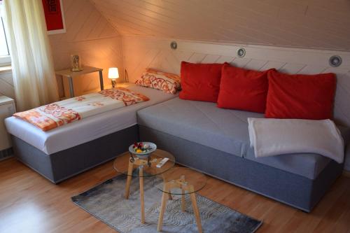 a bedroom with two beds with red pillows and a table at Gästehaus Bachra in Bachra
