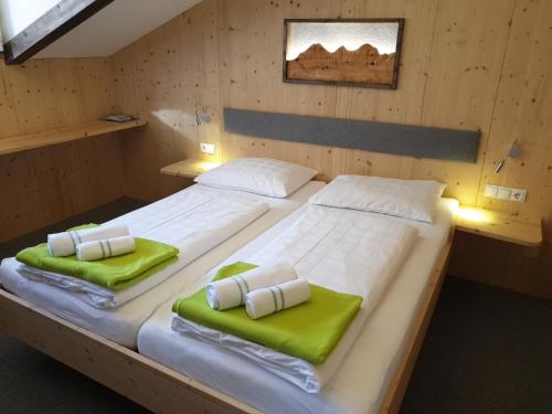 2 camas en una habitación de madera con cojines verdes en Berghotel Türlwand, en Ramsau am Dachstein