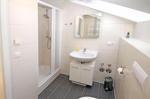 a white bathroom with a sink and a shower at Buesumer-Ring-Strandmuschel-501 in Kühlungsborn