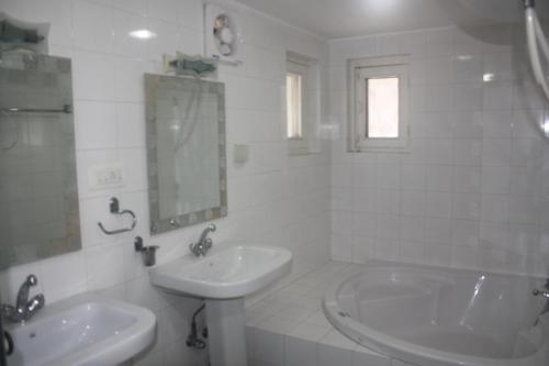a white bathroom with two sinks and a mirror at Snow Leopard Lodge in Srinagar