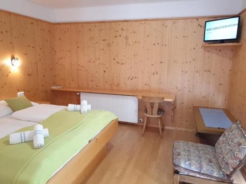 a room with two beds and a tv and a chair at Berghotel Türlwand in Ramsau am Dachstein