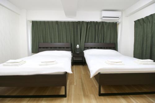 two beds in a room with green curtains at Uhome千駄木静雅民宿旅馆 in Tokyo