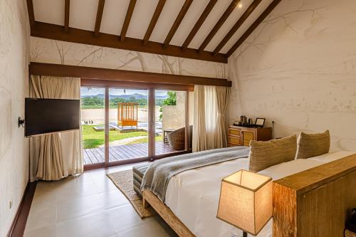 a bedroom with a bed and a sliding glass door at Meghauli Serai Chitwan National Park - A Taj Safari Lodge in Meghauli