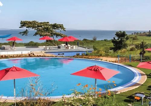 einen Pool mit roten Sonnenschirmen und dem Meer in der Unterkunft Aquarius Kigo Resort in Kigo