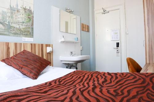 アムステルダムにあるHotel Asterisk, a family run hotelのベッドとシンク付きのホテルルーム