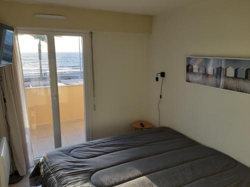 um quarto com uma cama e vista para o oceano em appartement Cavalaire face à la mer em Cavalaire-sur-Mer