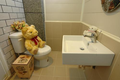 two teddy bears sitting on a toilet in a bathroom at 朝日民宿 可包棟 in Taitung City