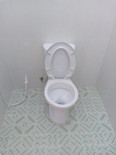 a white toilet in a bathroom with a tile floor at Homestay 89 New in Jepara
