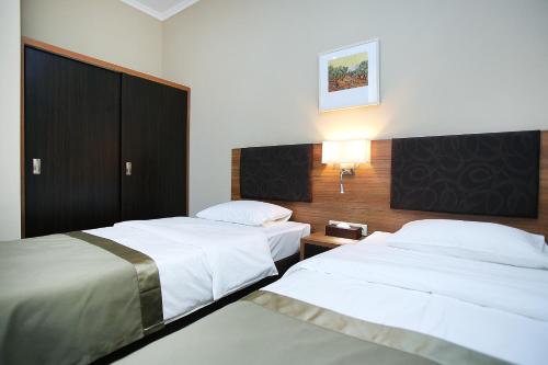 a hotel room with two beds and a night stand at Tskaltubo Plaza Hotel in Tskaltubo
