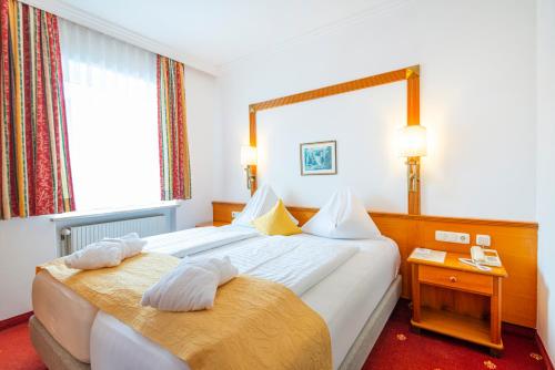 ein Hotelzimmer mit 2 Betten und einem Spiegel in der Unterkunft Hotel Germania Gastein - ganzjährig inklusive Alpentherme Gastein & Sommersaison inklusive Gasteiner Bergbahnen in Bad Hofgastein