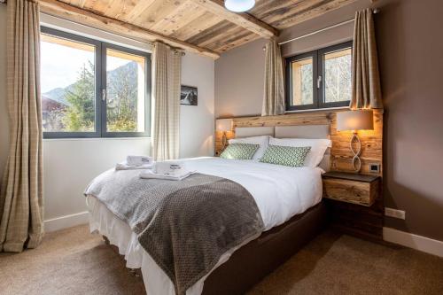 une chambre avec un grand lit et deux fenêtres dans l'établissement Chalet des Amis appt 1 - Chamonix All Year, à Chamonix-Mont-Blanc