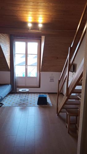Cette chambre mansardée dispose d'un escalier et d'une fenêtre. dans l'établissement Appartement Sainte Marie de Campan - Résidence le Vieux Village, à Sainte-Marie-de-Campan