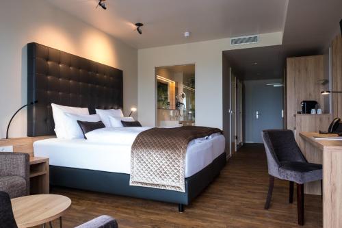 NeukenrothにあるRebhan's Business und Wellness Hotelのベッドルーム1室(大型ベッド1台、テーブル、椅子付)