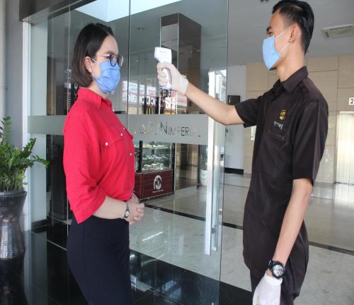a woman and a man wearing masks in front of a glass door at Aston Imperial Bekasi Hotel & Conference Center in Bekasi