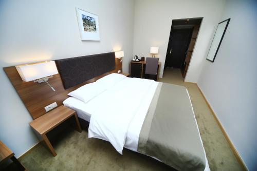 a bedroom with a large white bed and a desk at Tskaltubo Plaza Hotel in Tskaltubo