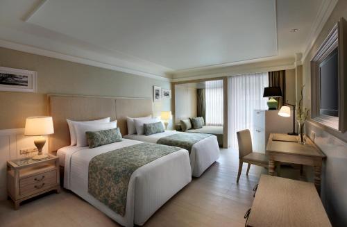 a hotel room with two beds and a desk at Amari Hua Hin in Hua Hin